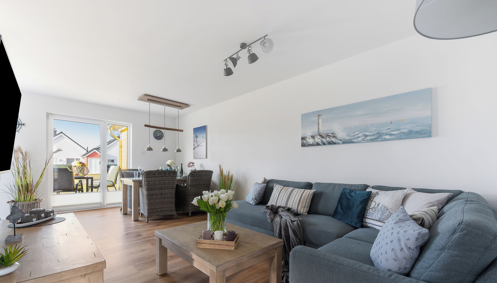 Una sala de estar moderna con un sofá gris, una mesa de centro de madera y vistas al exterior a través de un ventanal.