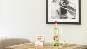 A framed photograph of a ship's anchor on a dock, a bottle of hot sauce, a glass, and a sign on a wooden table.