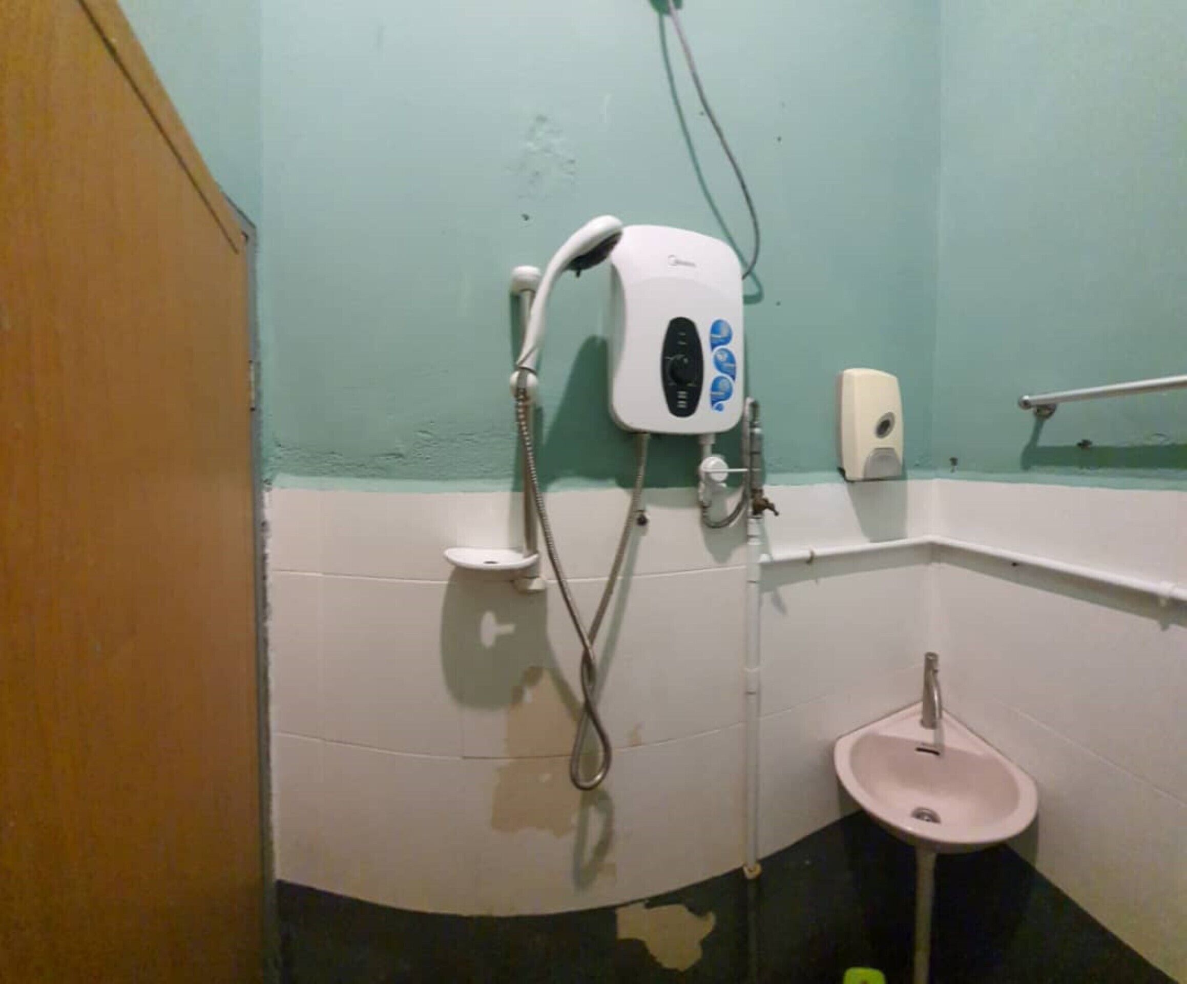 A bathroom with a shower, a sink, and a soap dispenser.