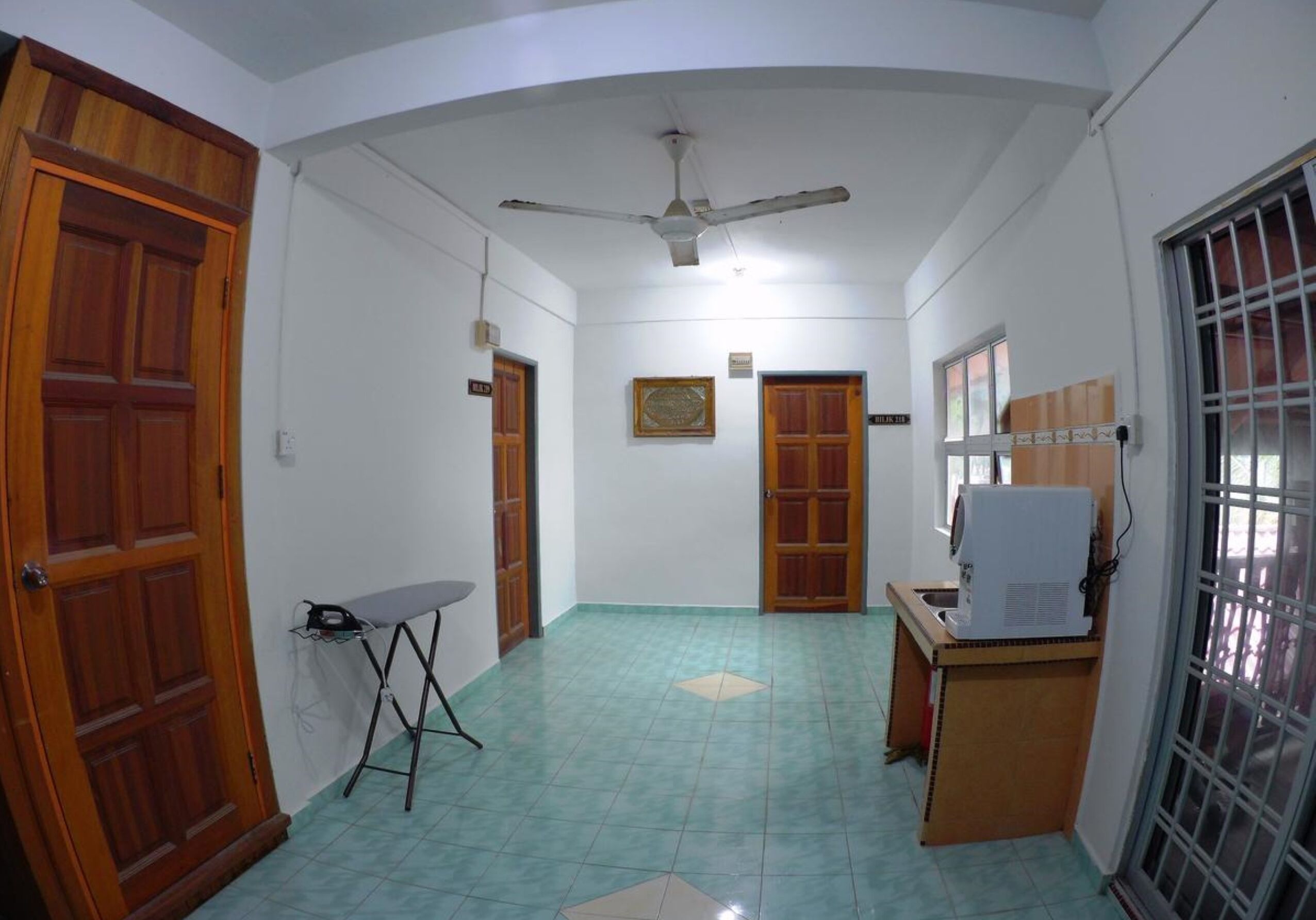 A hallway with a ceiling fan, wooden doors, and a tiled floor.