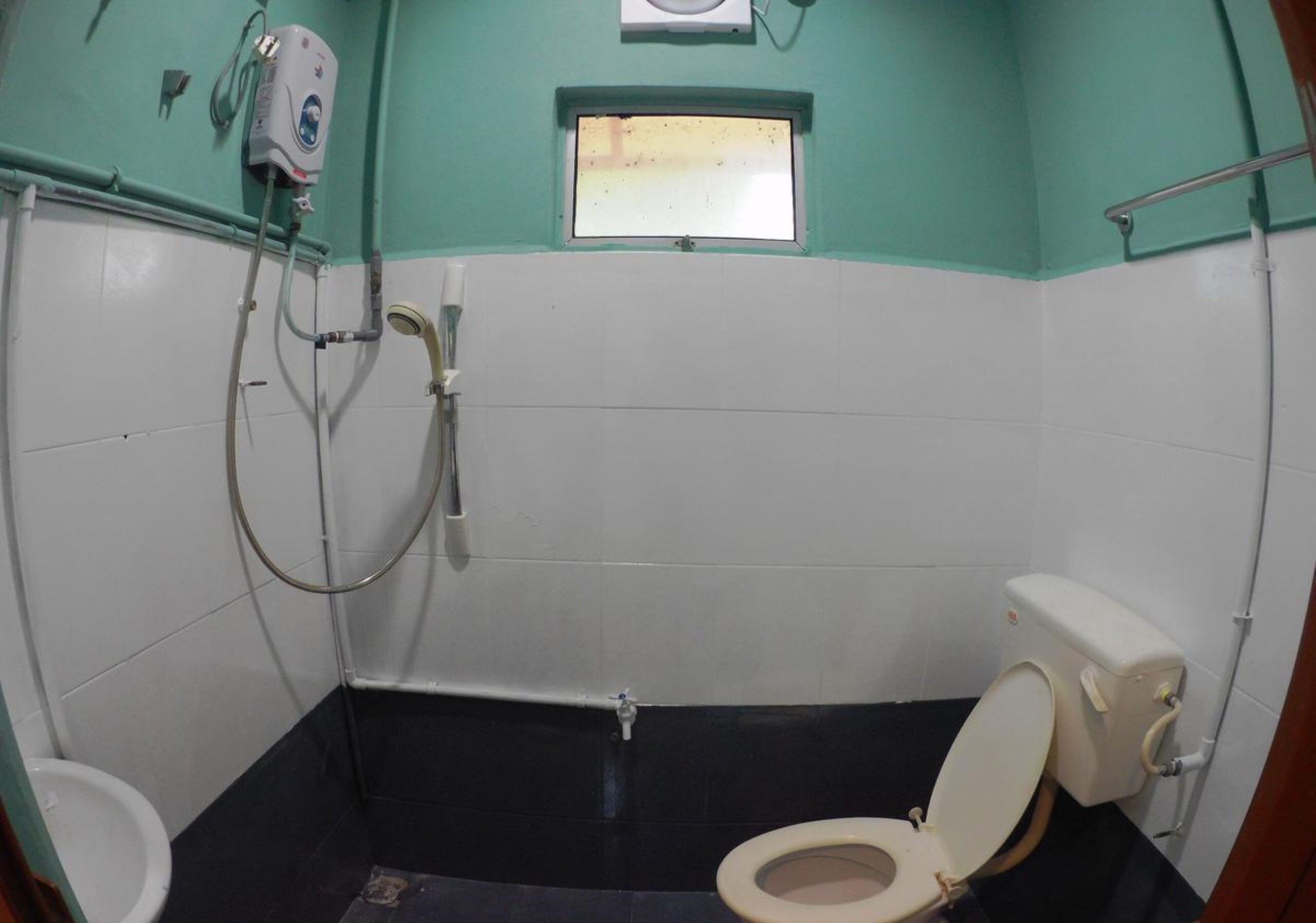 A small, compact bathroom with a toilet, bidet, and a window.