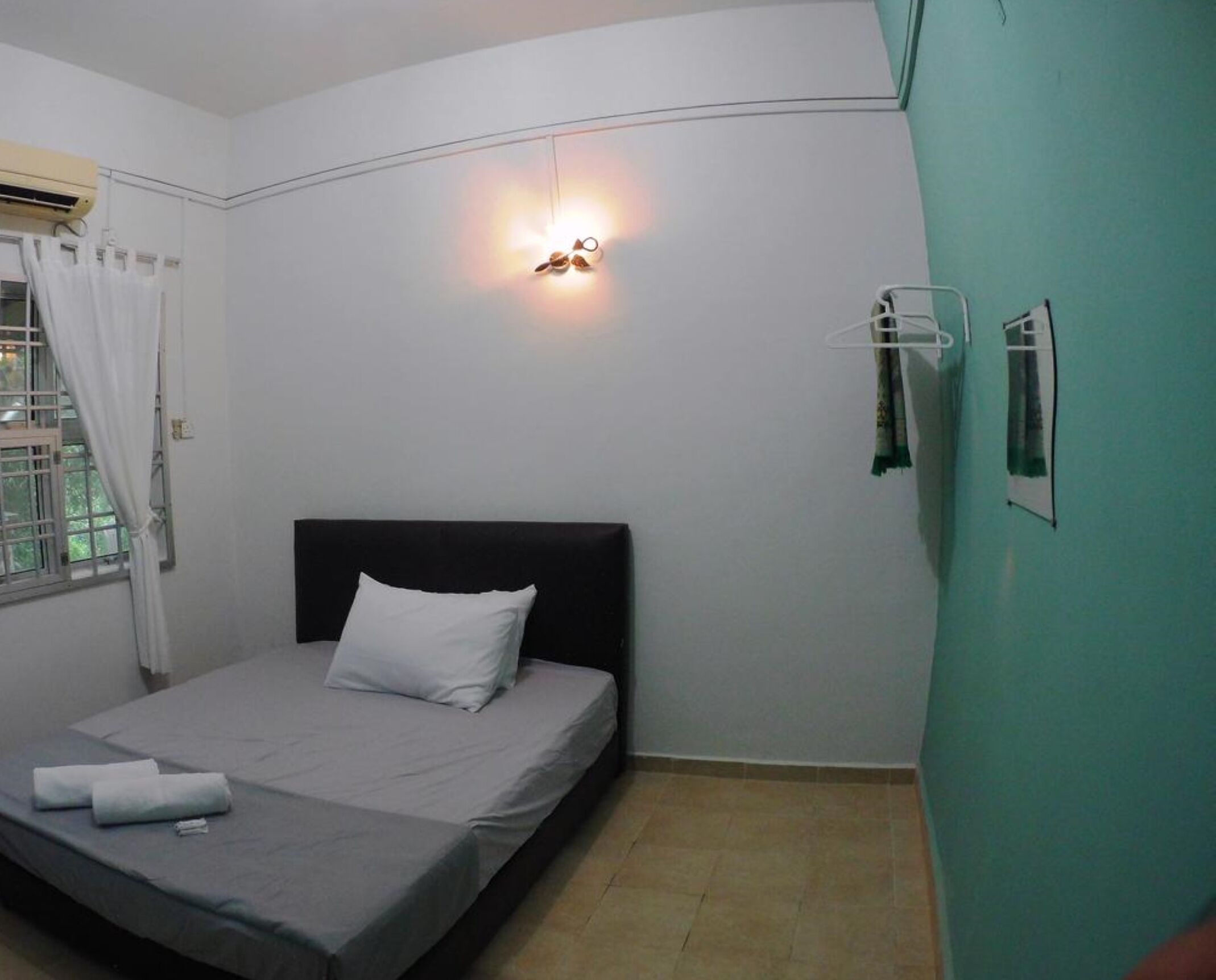 A single bed with a black headboard and white pillow in a room with teal walls.