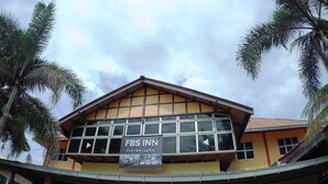 Un edificio con il cartello dell'FBS Inn, caratterizzato da ampie finestre e una facciata gialla.