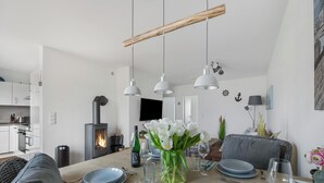 Une cuisine moderne avec des armoires blanches, une cuisinière encastrée et des luminaires suspendus.