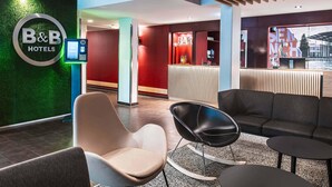 A hotel lobby with a reception desk, seating area, and a bar. - B&B Hotel München-Messe (Aschheim)