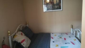 A bedroom with a bed, a nightstand, a lamp, and a framed picture on the wall.