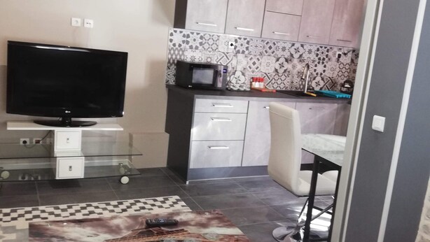 Een moderne woonkamer met een flatscreen televisie, een glazen salontafel en een bank.