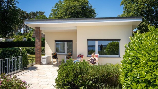 A modern house with a patio, two windows, and a brick chimney. - Ferienhaus Anja - FH Anja (Plau am See)