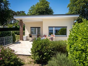 Une maison moderne dotée d’un patio, de deux fenêtres et d’une cheminée en briques.