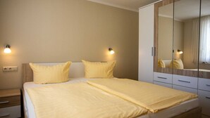 A bedroom with a double bed, two bedside tables, a wardrobe, and wall-mounted lights. - Ferienhaus Anja - FH Anja (Plau am See)