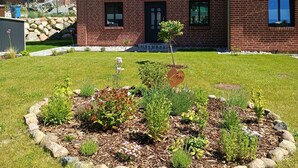 A two-story brick building with a well-maintained lawn and garden in front. - Ferienwohnung Junis, Deutschland (Sassnitz)