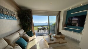 Ein modernes Wohnzimmer mit einer Couch, einem Couchtisch und Blick ins Freie.