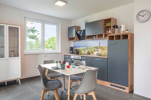 Una cocina moderna con comedor, que cuenta con electrodomésticos integrados, un amplio ventanal y un reloj en la pared.
