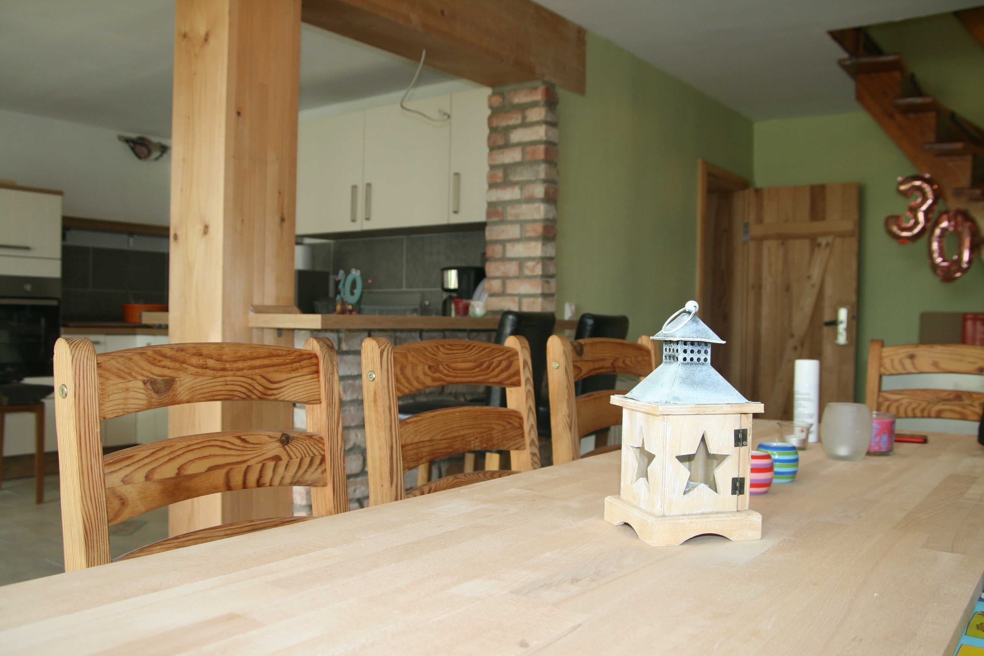 Ein Holzespeisesaal mit Stühlen, einer Laterne und einer Küche im Hintergrund.