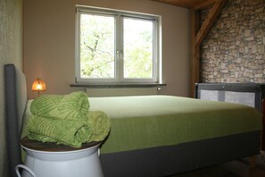 Ein Schlafzimmer mit einem Bett, einem Fenster und einer Steinwand.