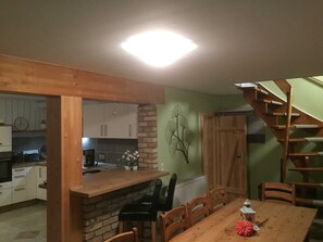 Ein Essbereich mit Holztisch und Stühlen, einer Wand aus Ziegelsteinen und einer Treppe, die zu einer oberen Ebene führt.