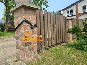 Ein hölzernes Tor mit einer Ziegelstütze und einem Willkommensschild.