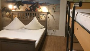 Una habitación con una litera, una cama con dos almohadas y un mural de caballos en la pared.