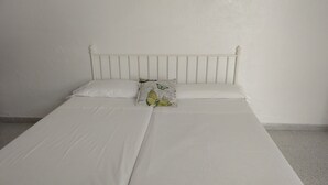 Una habitación sencilla con una cama individual, cabecera lisa y un cojín con diseño de mariposa.