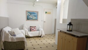 Una habitación con un sofá, un armario, un cuadro y una puerta con la leyenda 'EL GARAXAL'.