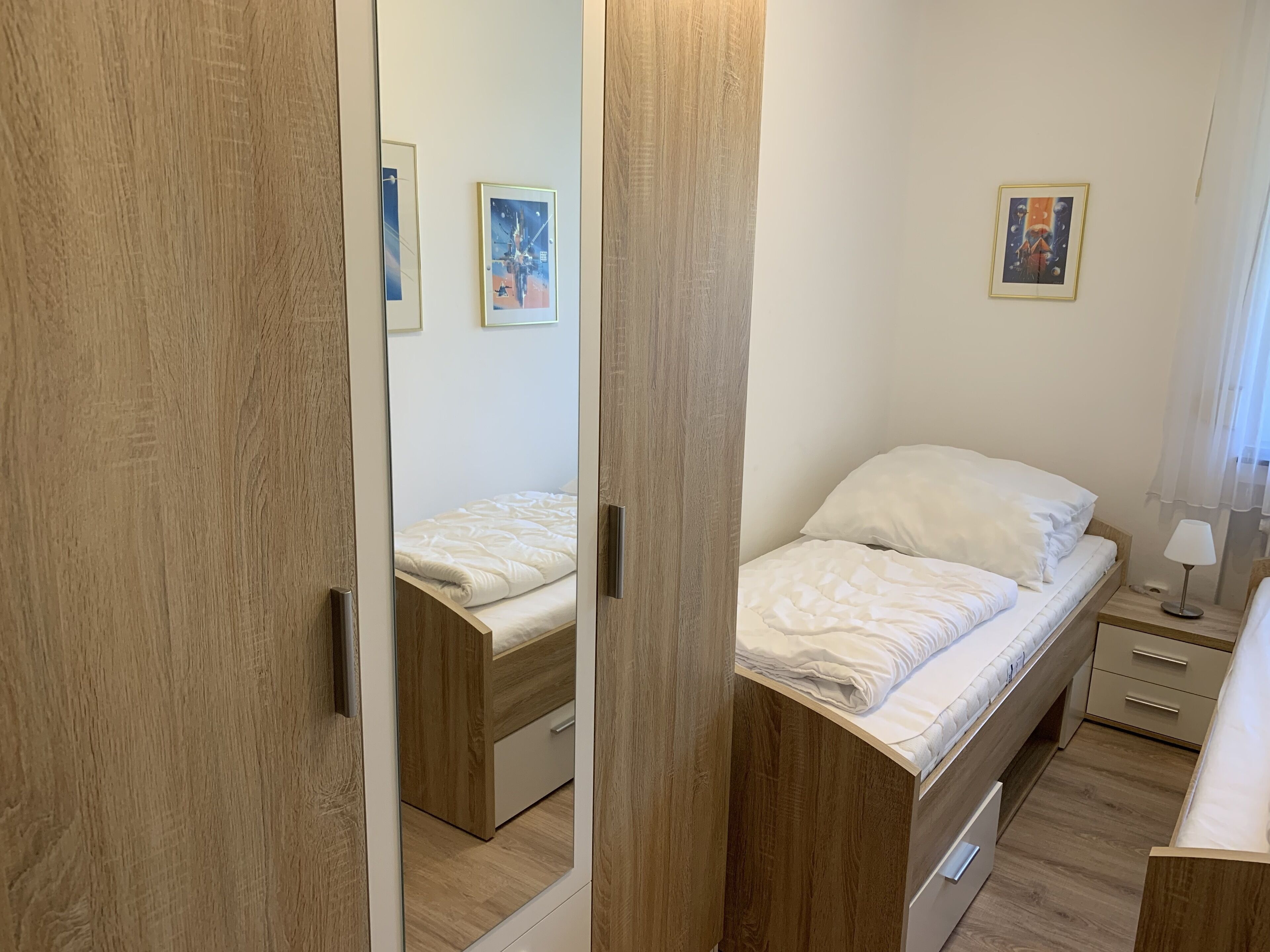 Une chambre à coucher avec un lit, une table de chevet, une lampe et un miroir.