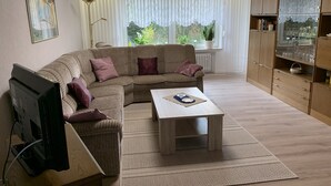 A modern living room with a sectional sofa, a coffee table, a TV, and a bookshelf.