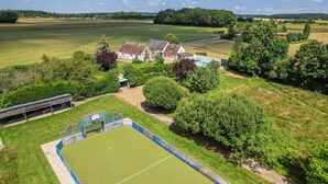 An aerial view of a property with a large green sports field, a basketball court, and a building with a sloped roof. - Crazy Villa Luigny (28) - Heated pool - City Stade - 1h20 Paris - 30P (Luigny)