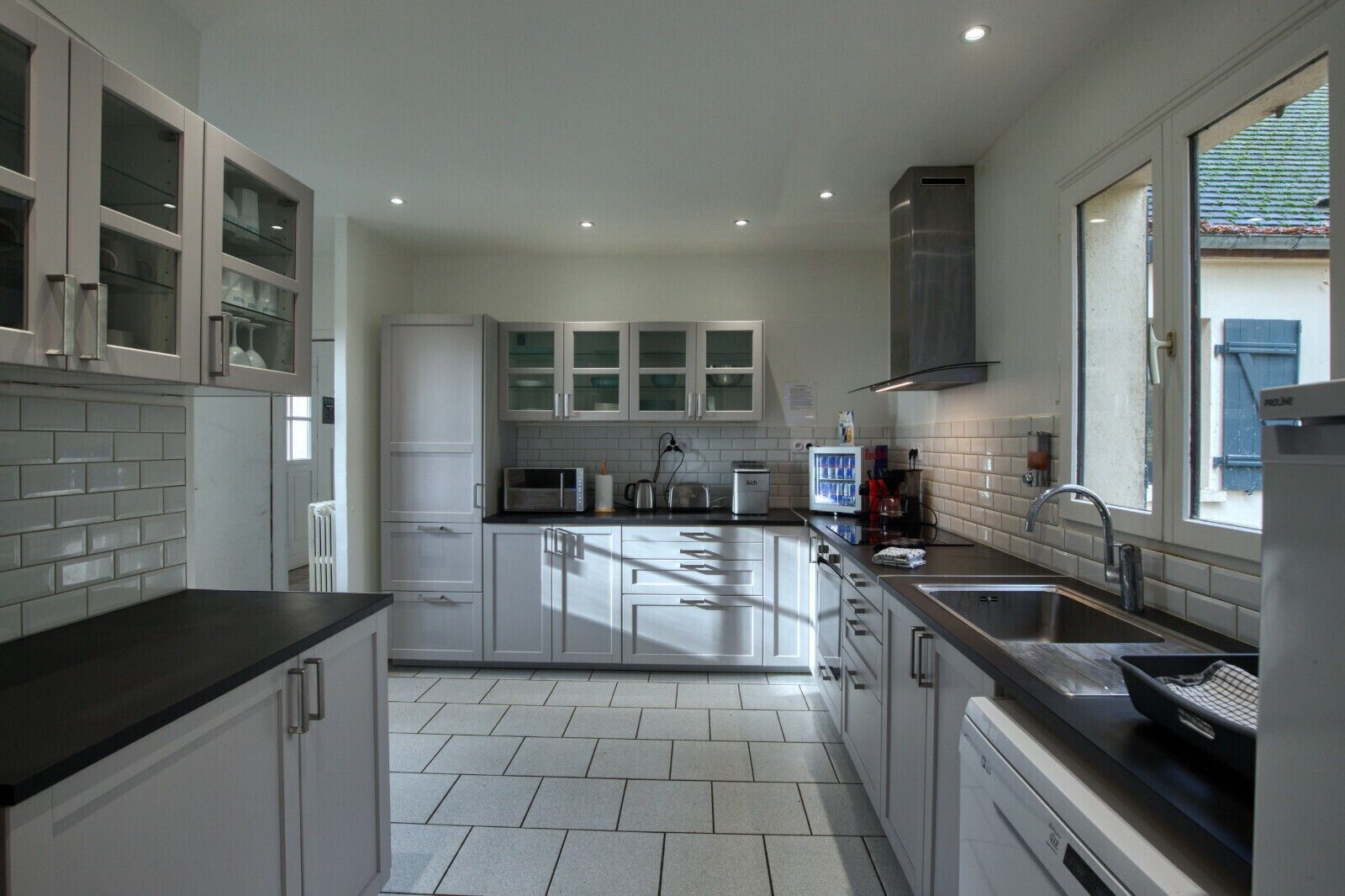 A modern kitchen with white cabinets, a black countertop, and a stainless steel sink.