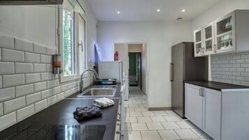 Een moderne keuken met een zwart aanrecht, een roestvrijstalen spoelbak en grijze kastjes.