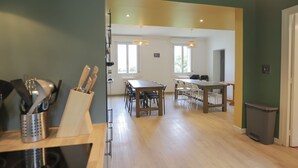 A spacious dining area with a long wooden table and chairs, a kitchen area with a sink and utensils, and a trash bin. - Crazy Villa Radar (89) - Heated pool - Multisports field - 2h Paris - 30p. (Saint-Cyr-les-Colons)