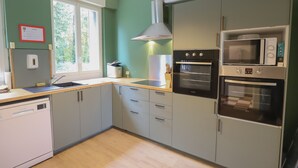 A modern kitchen with grey cabinets, a dishwasher, a sink, a stove, and a microwave. - Crazy Villa Radar (89) - Heated pool - Multisports field - 2h Paris - 30p. (Saint-Cyr-les-Colons)