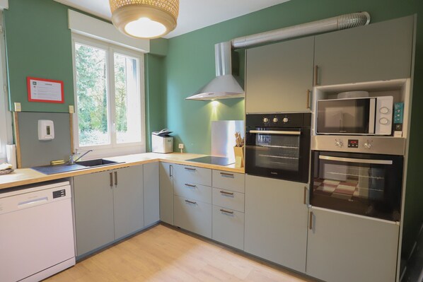 Een moderne keuken met grijze kastjes, een vaatwasser, een spoelbak, een fornuis en een magnetron.