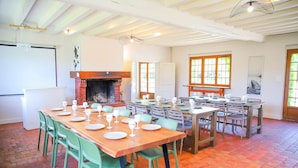Comedor con suelo de ladrillo, mesas de madera y sillas verdes.
