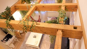 Ein Zimmer mit Holzbalkendecke, einem weißen Tisch und einem grauen Sofa.