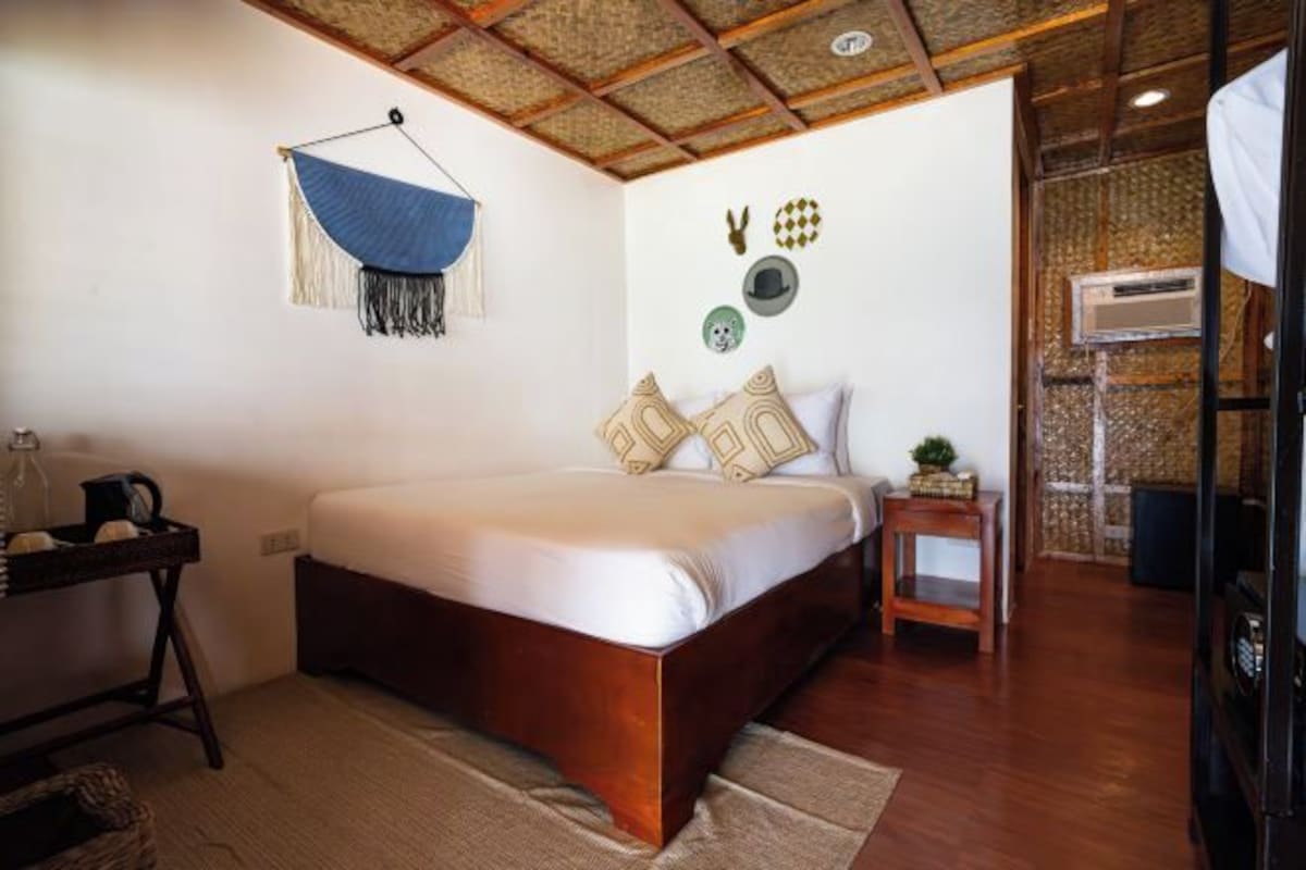 A bedroom with a wooden bed, a hanging blue fabric, and wall decorations including hats and a dog figurine.