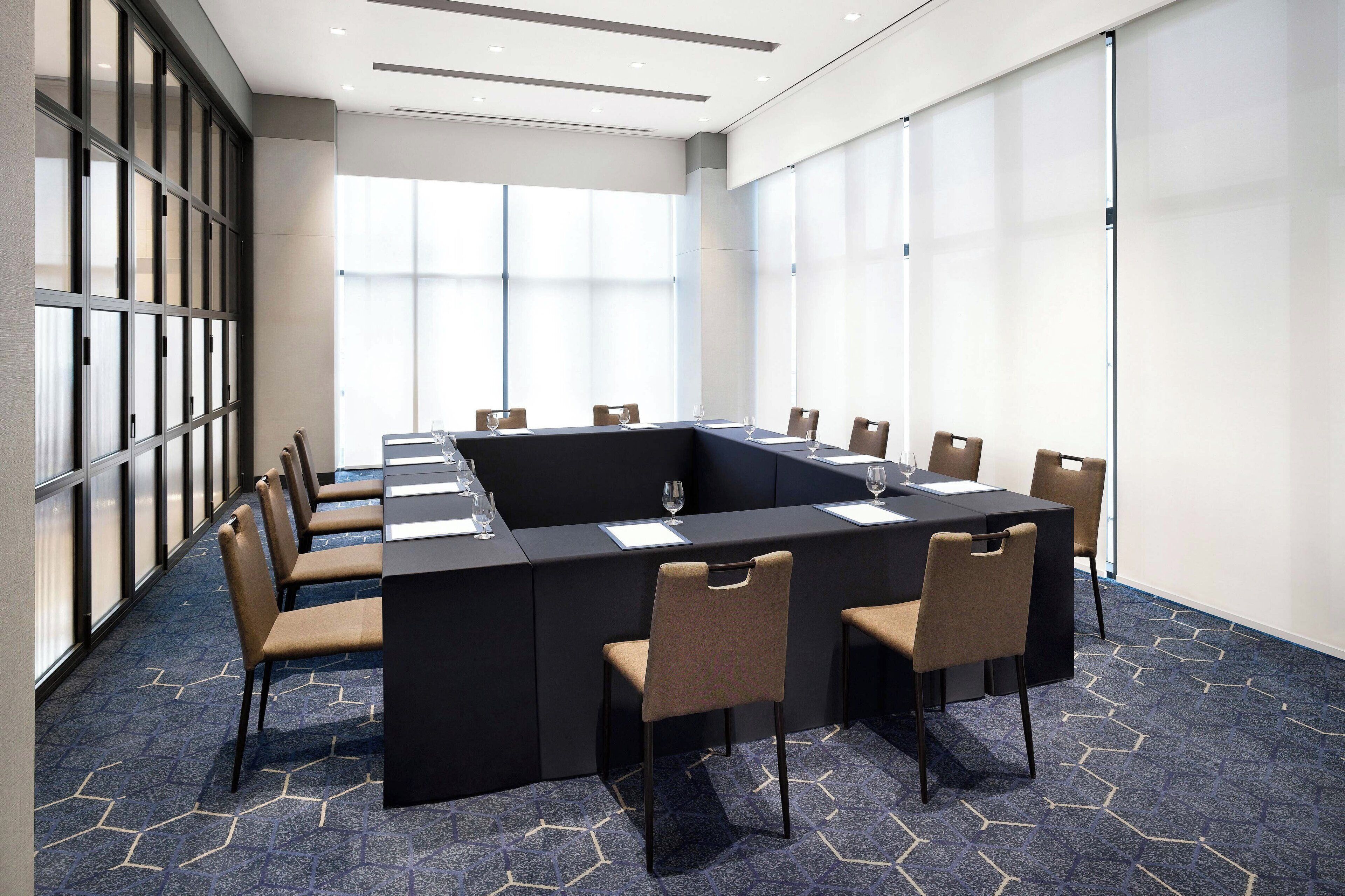 A conference room with a large table, chairs, and a glass partition.