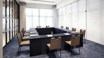 A conference room with a large table, chairs, and a glass partition.