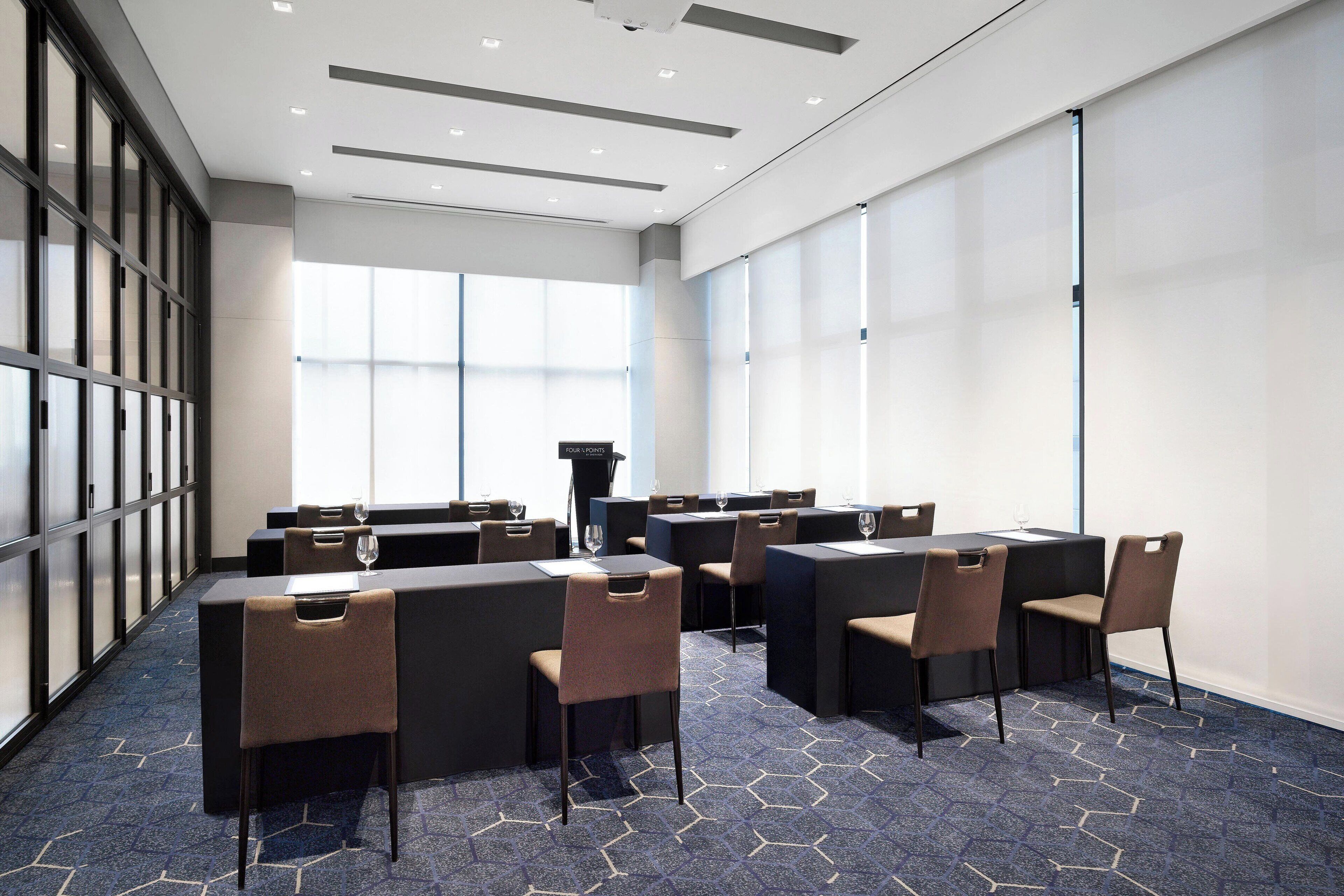 A conference room with a long table, multiple chairs, and a podium.