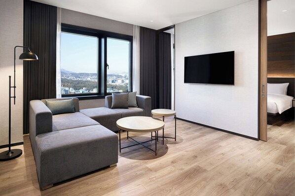 A modern hotel room with a sectional sofa, two round tables, a flat-screen TV, and a city view. - Four Points by Sheraton Josun, Seoul Myeongdong (Seoul)