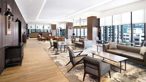 Un hall espacioso con muebles modernos, amplias ventanas con vistas a la ciudad y suelo de madera.