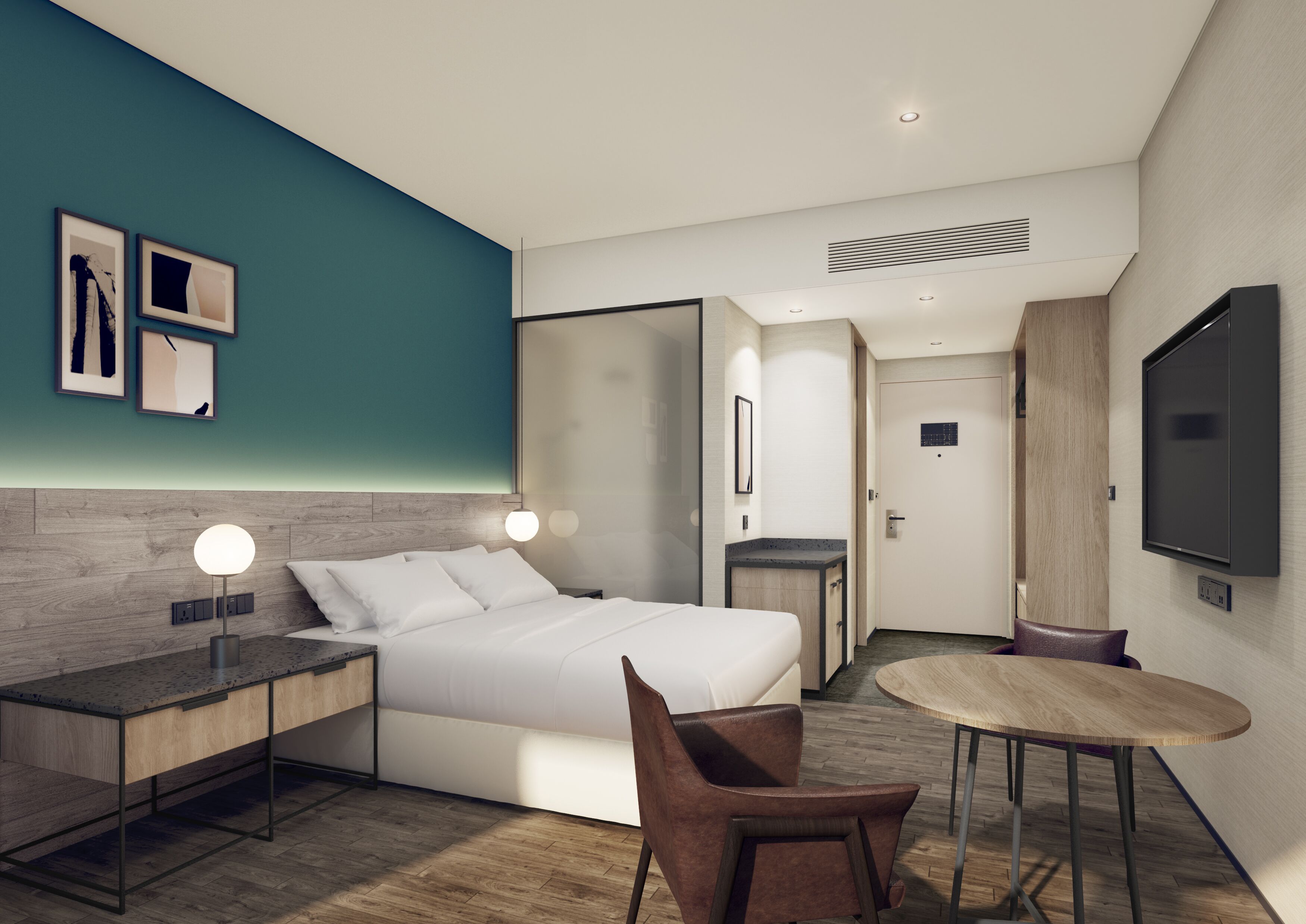 A modern hotel room with a bed, bedside table, lamp, chair, and a small round table.
