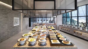 Montaje de bufé con diversos platos y una cocina moderna al fondo.