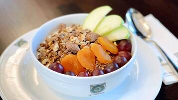 A bowl of cereal with fruits and nuts on a white plate.