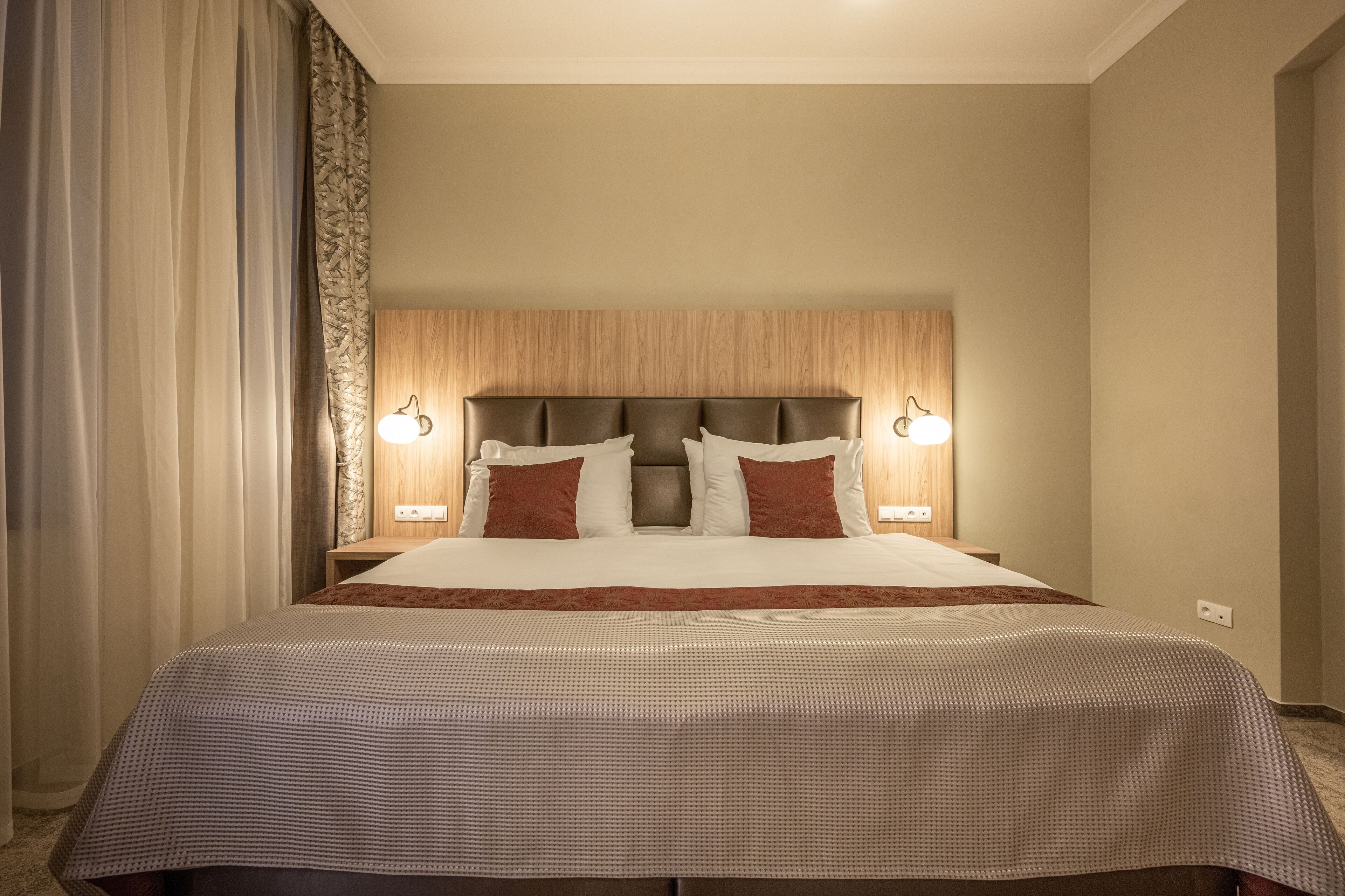 Habitación de hotel con una cama grande, dos mesitas de noche y un cabecero con iluminación integrada.