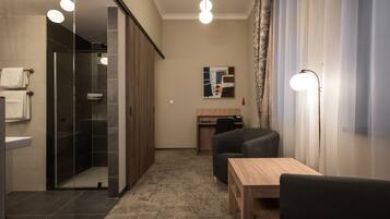 Ett modernt hotellrum med dusch, skrivbord och en sittgrupp.