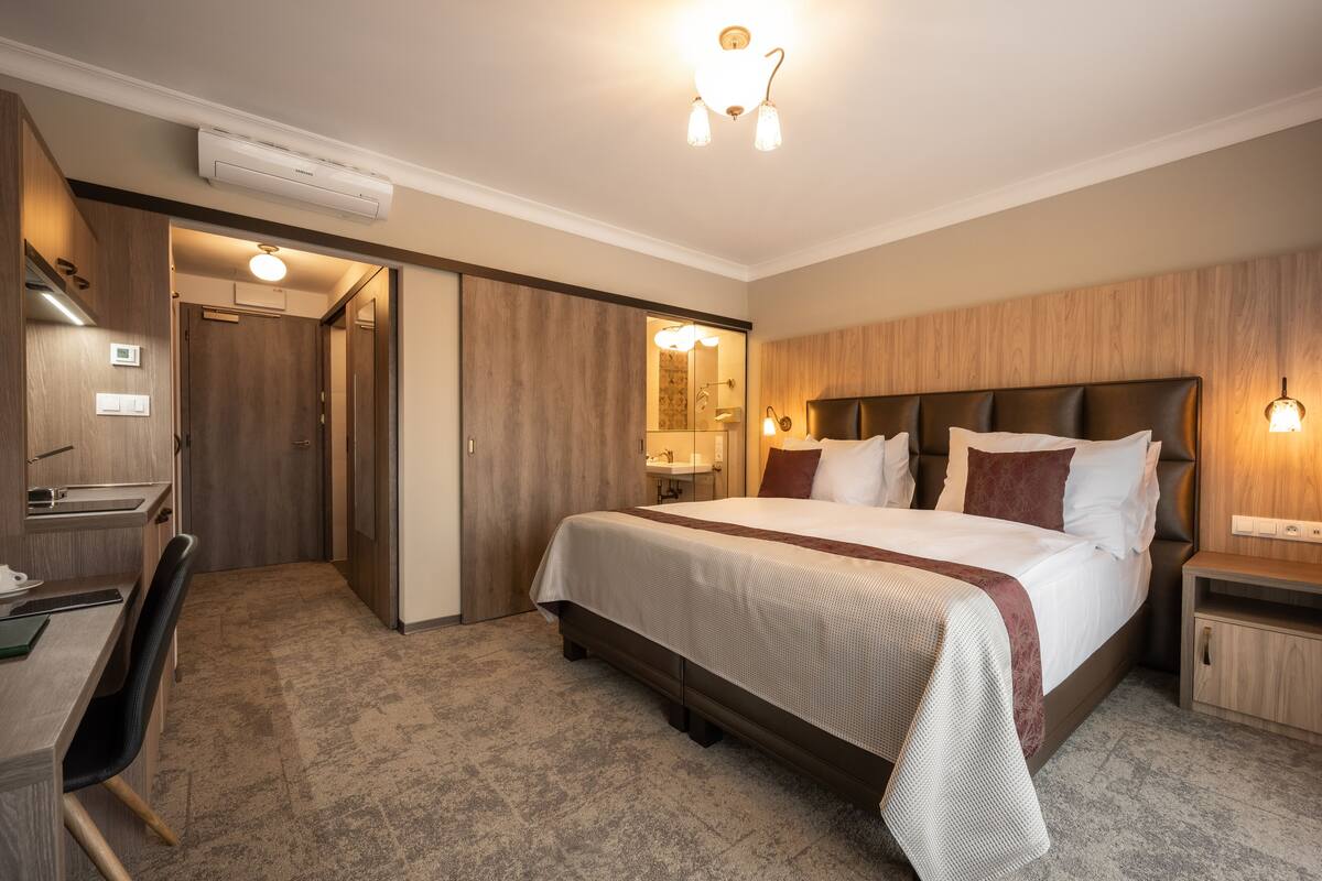A hotel room with a large bed, a desk, a wardrobe, and a bathroom.