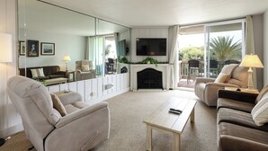 Una sala de estar con chimenea, televisión y un espejo grande.