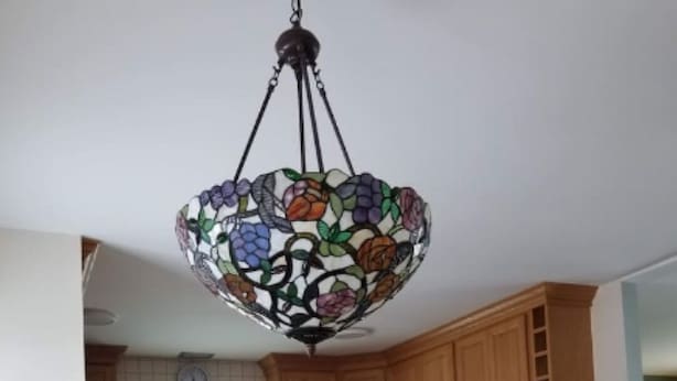 A kitchen with wooden cabinets, a stove, and a hanging chandelier.