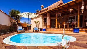A swimming pool with lounge chairs and a table with wine glasses and a bottle.