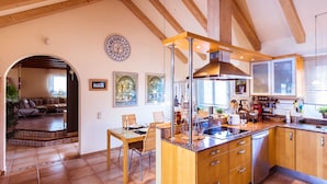 A kitchen with wooden cabinets, a central island, and a dining area with chairs and a table.